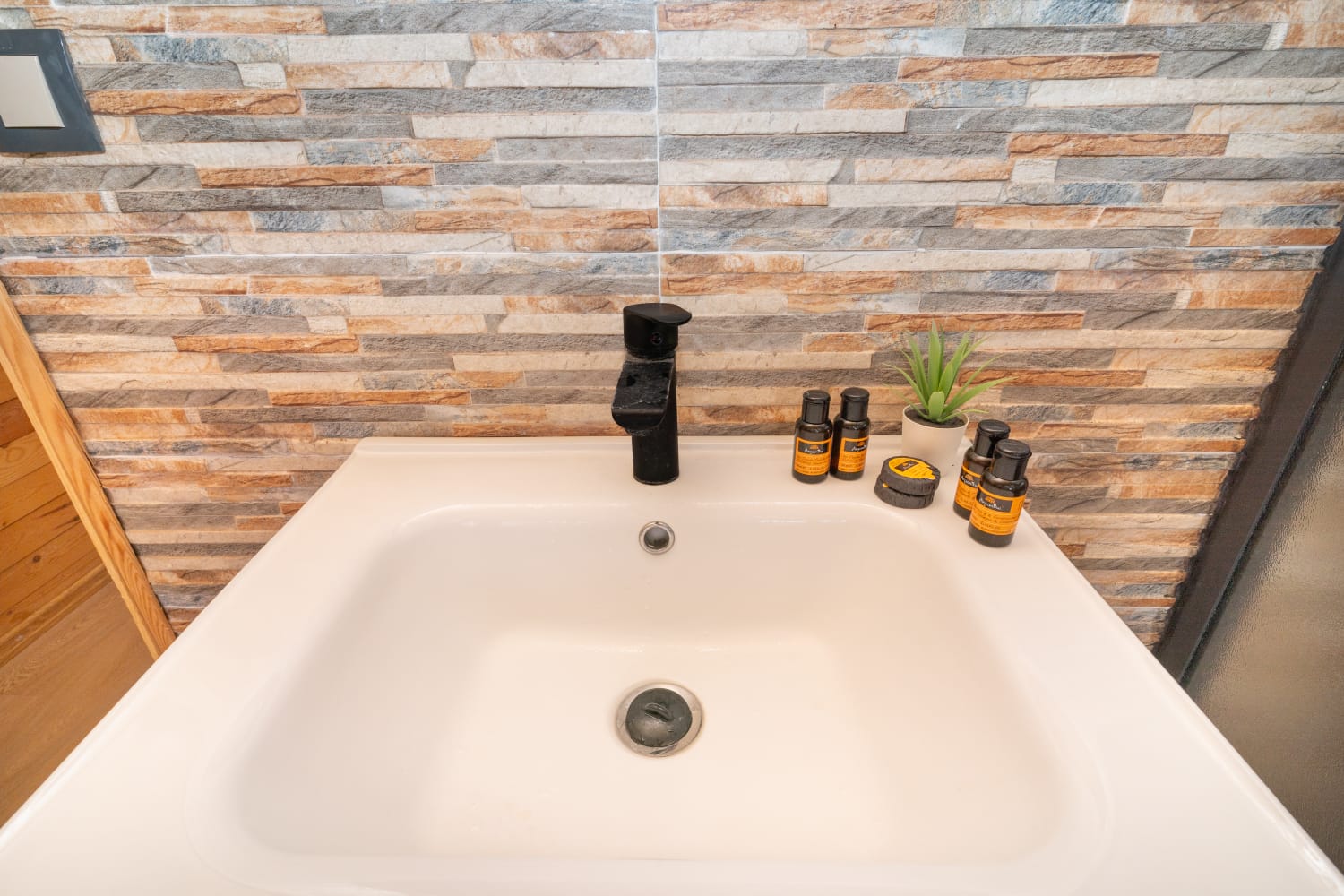 Private bathroom with stone-effect wall and modern basin