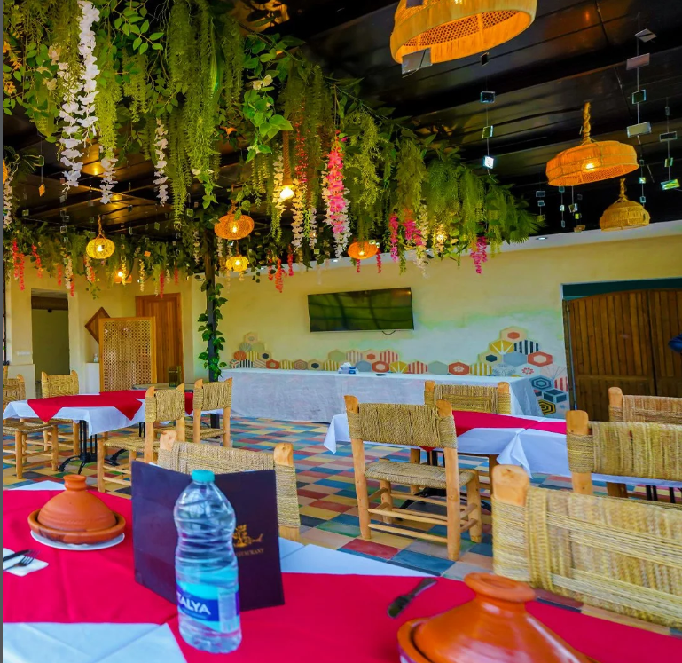 Restaurant dining room with hanging greenery and traditional tables at Jnane Riad
