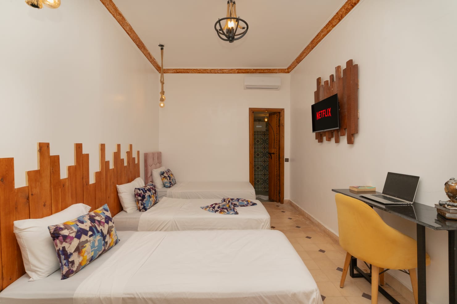 Spacious family room with three beds and traditional detailing at Jnane Riad