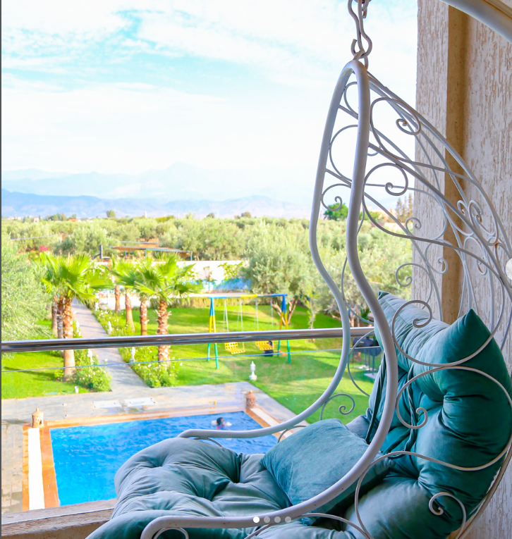 View over the swimming pool and palm gardens toward the Atlas foothills at Jnane Riad