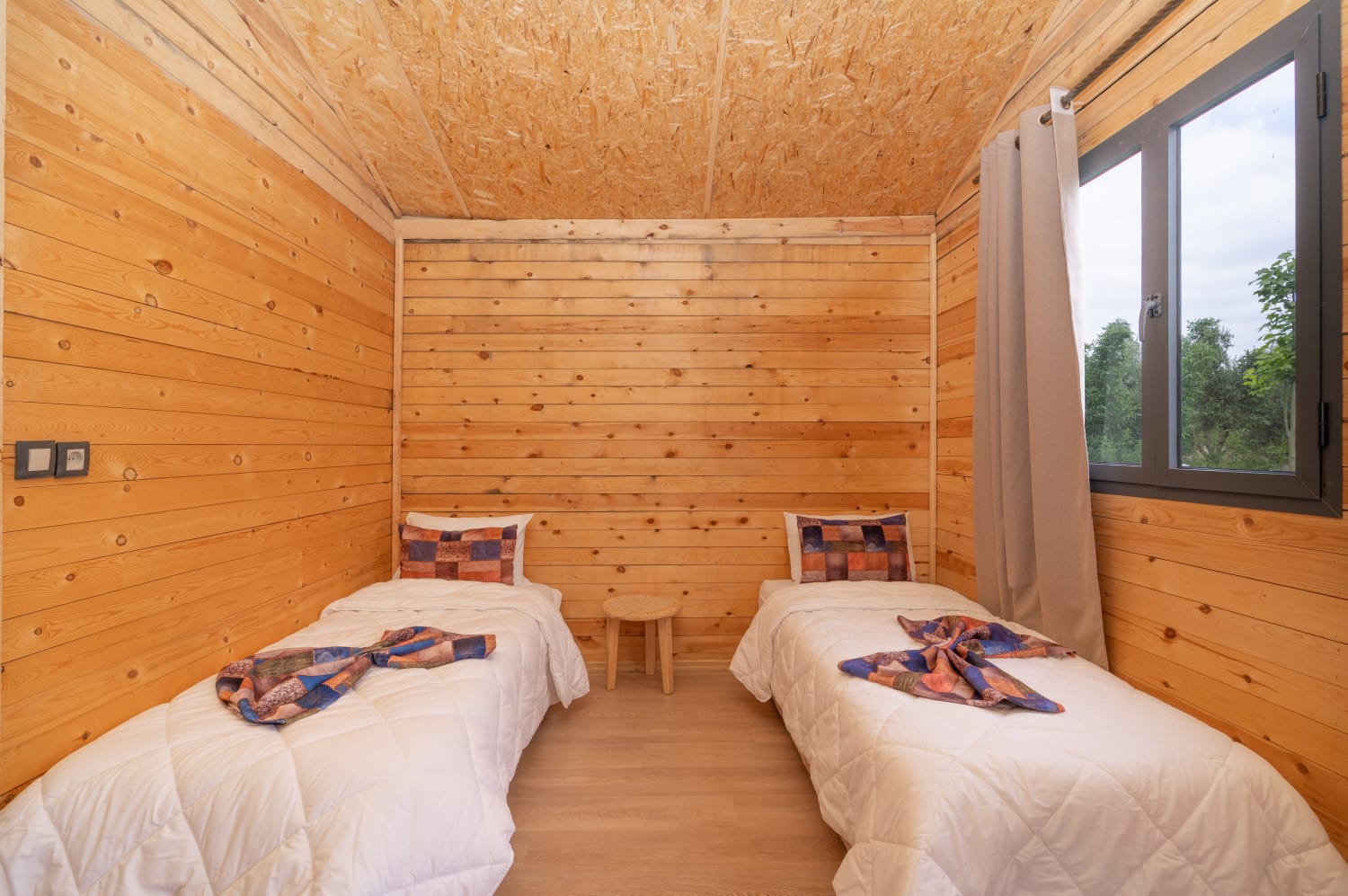 Twin beds beneath a pitched wooden ceiling in Villa Ouarzazate